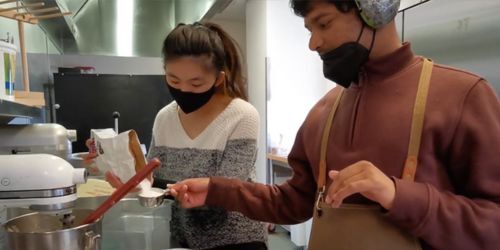 SFSU Inclusion student working with a teacher in a kitchen