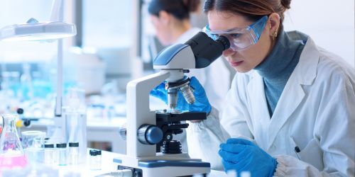 Scientist working in a lab, looking into a microscope
