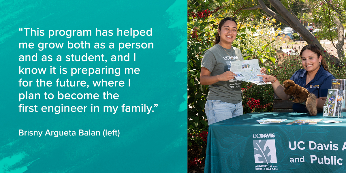 A student stands next to a table in the arboretum holding up a map.