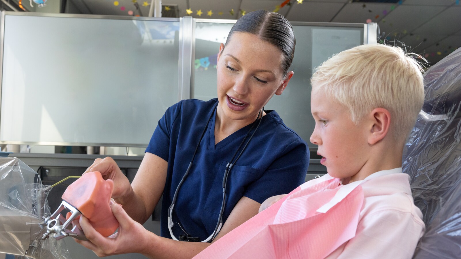 A dental student looks at a dental mold with a patient.