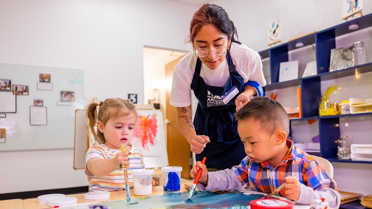 An NAU student oversees two children as they make a painting. An NAU student oversees two children as they make a painting.